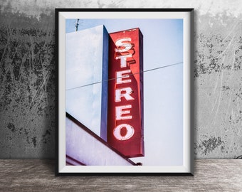 May include: A vintage red sign with white neon lettering that reads "STEREO" against a blue sky.