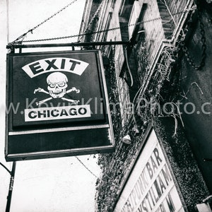 Op de afbeelding: Zwart-wit bord met de woorden "Exit Chicago" en een schedel met gekruiste beenderen.