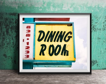 May include: A vintage yellow sign with black lettering that reads "DINING ROOM" against a blue sky. The sign is attached to a blue and white structure with red numbers.