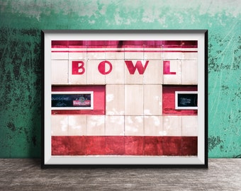 May include: Framed photograph of a bowling alley facade. The word "BOWL" is in large red letters. Below, there are two small signs with the Bud Light and Miller Lite logos. The building has a red and white color scheme.