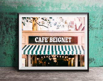 May include: A framed photograph of a cafe with a green and white striped awning. The sign above the awning reads "Cafe' Beignet".