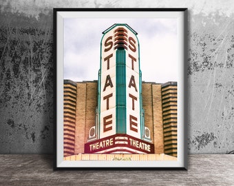 May include: A vintage-style photo of a theater marquee with the word "STATE" in large, illuminated letters. The marquee is decorated with green and white trim and has the words "THEATRE" on either side of the sign.