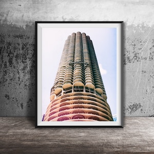 May include: A framed photograph of a tall, cylindrical building with a unique, rounded design. The building is made of concrete and has many windows. The photograph is taken from a low angle, looking up at the building.