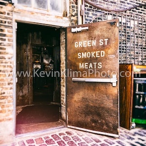 Może przedstawiać: Rustykalne metalowe drzwi z napisem "Green St Smoked Meats". Drzwi są otwarte, a za nimi znajduje się ceglana ściana.