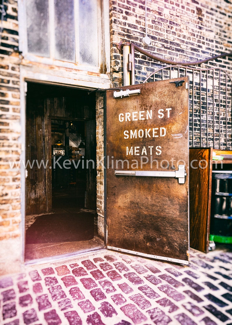 Może przedstawiać: Rustykalne metalowe drzwi z napisem "Green St Smoked Meats". Drzwi są otwarte, a za nimi znajduje się ceglana ściana.
