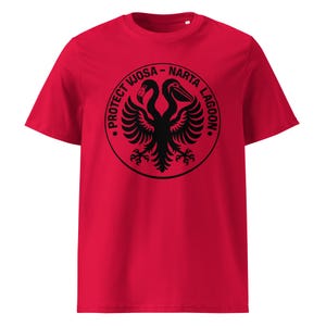 May include: A bright red short-sleeved t-shirt featuring a black circular graphic on the chest. The design depicts a double-headed bird with wings spread, surrounded by the text "PROTECT VJOSA - NARTA LAGOON" in a bold, circular font.