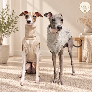 Pode incluir: Dois galgos italianos vestindo camisolas de malha. O cão à esquerda usa uma camisola de gola alta canelada bege, enquanto o cão à direita usa uma camisola de gola alta de malha trançada cinza claro. Um logótipo circular com o texto KKP15 é visível.