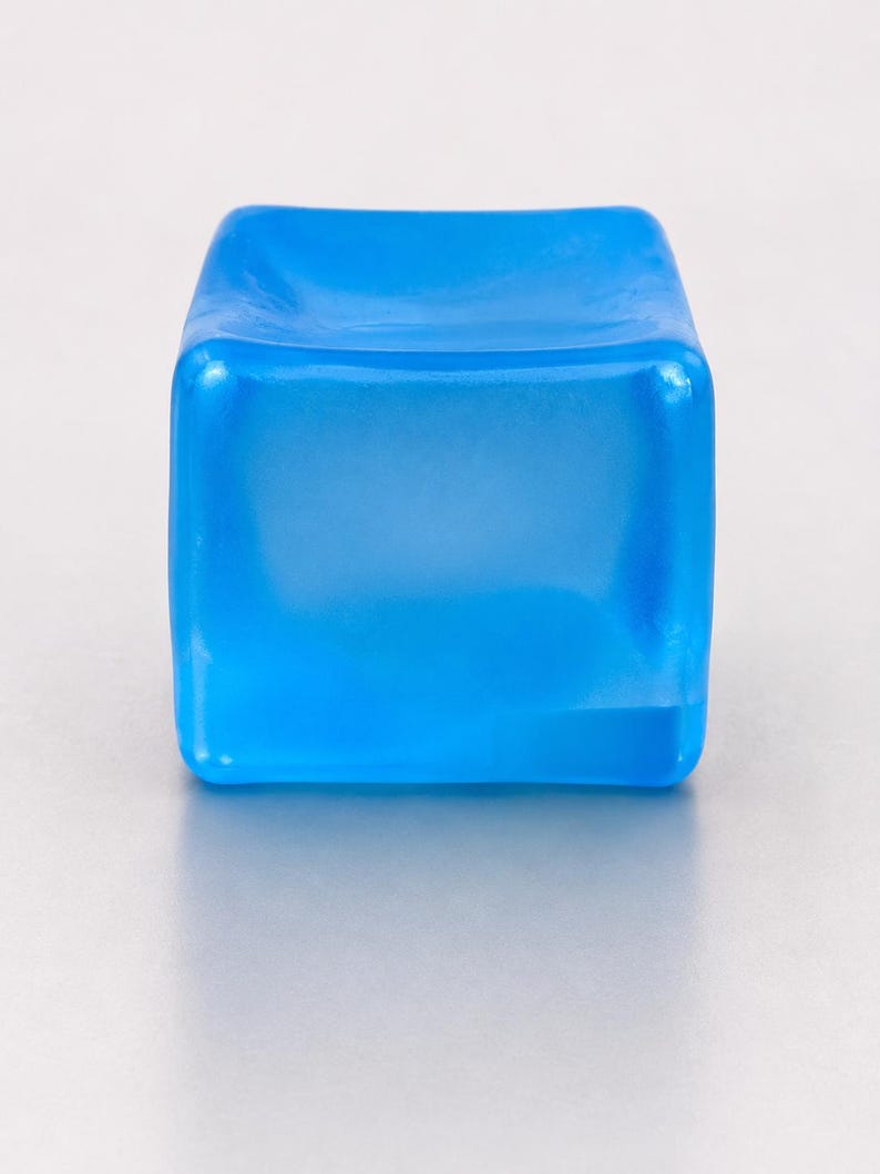 Op de afbeelding: Een klein, vierkant object gemaakt van doorschijnend blauw materiaal. Het item heeft een glad, licht concaaf bovenoppervlak met afgeronde randen en hoeken, en vertoont een uniforme, levendige azuurblauwe kleur in zijn solide, blokvorm.
