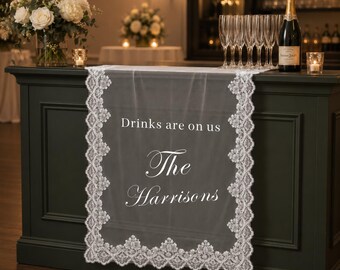 Transparant kanten barbord voor de bruiloft, stoffen banner met gepersonaliseerde achternaam, receptiedecoratie met de tekst "Drankjes van ons"