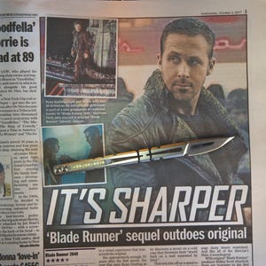 May include: A newspaper clipping with the headline "IT'S SHARPER" and the text "Blade Runner sequel outdoes original." The image features a photo of Ryan Gosling and a futuristic knife.