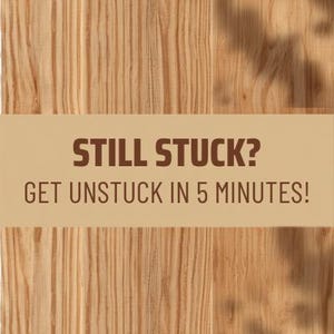 May include: A light brown rectangular sign with a wood grain pattern background. The text in dark brown reads STILL STUCK? GET UNSTUCK IN 5 MINUTES! The sign features a solid tan horizontal band across the centre containing the text.