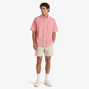 May include: A short-sleeved button-down shirt featuring a red and white gingham check pattern, paired with solid beige shorts, white crew socks, and white sneakers. The shirt has a classic collar and a full-length front button closure.