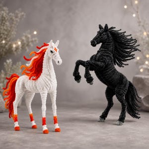 May include: Two horse figurines crafted from pipe cleaners. One horse is white with a vibrant orange and red mane, tail, and lower legs. The second horse is solid black, depicted in a rearing pose with a flowing mane and tail texture.