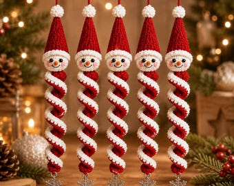May include: Five identical crocheted Christmas ornaments hanging vertically. Each features a snowman head with a red pointed hat, a long red and white spiral body, and a small silver-toned metal snowflake charm attached to the bottom.