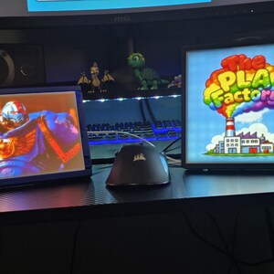 May include: Two rectangular light boxes with black frames. The left box displays a blue armoured figure with gold accents. The right box features a factory illustration with a rainbow cloud and the text The PLA Factory in colourful letters.