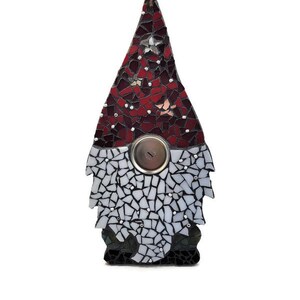 Op de afbeelding: Een moza&iuml;ek kabouter ornament met een rode en witte puntmuts, een knoopneus en een witte baard. De kabouter is gemaakt van kleine, onregelmatig gevormde stukjes glas in tinten rood, wit en zwart. Een bruin touwtje is bevestigd om op te hangen.