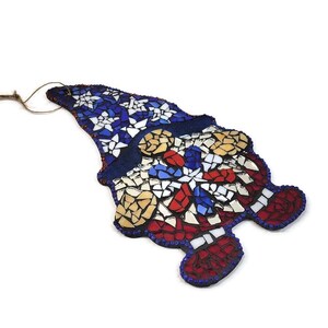 May include: A mosaic gnome ornament with a red, white, and blue design. The gnome's hat is decorated with white stars on a blue background. The gnome's body is decorated with red, white, and blue mosaic tiles.