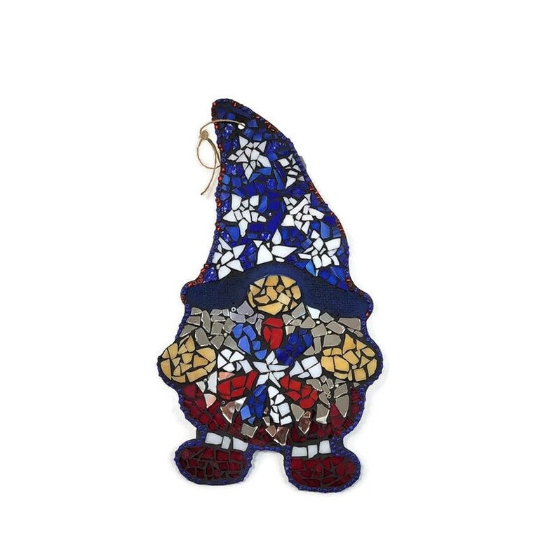 May include: A mosaic gnome ornament with a blue, white, and red star design. The gnome is wearing a blue hat with white stars and holding a red, white, and blue star in its hands.