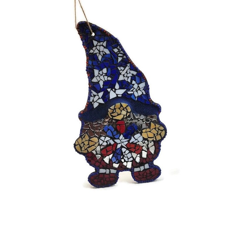 May include: A mosaic gnome ornament with a blue hat decorated with white stars. The gnome's body is decorated with red, white, and blue mosaic tiles.