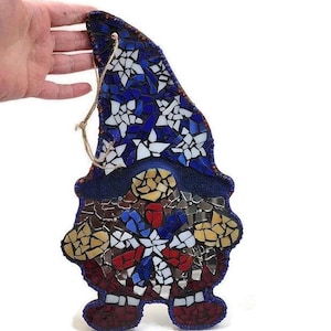 May include: A mosaic gnome ornament with a blue, white and red star pattern on the hat and a red, white and blue snowflake pattern on the body.