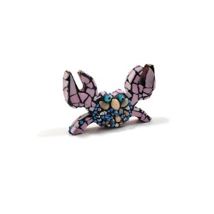 May include: A pink mosaic crab figurine with blue and white eyes. The crab is made of small pieces of glass and shell.