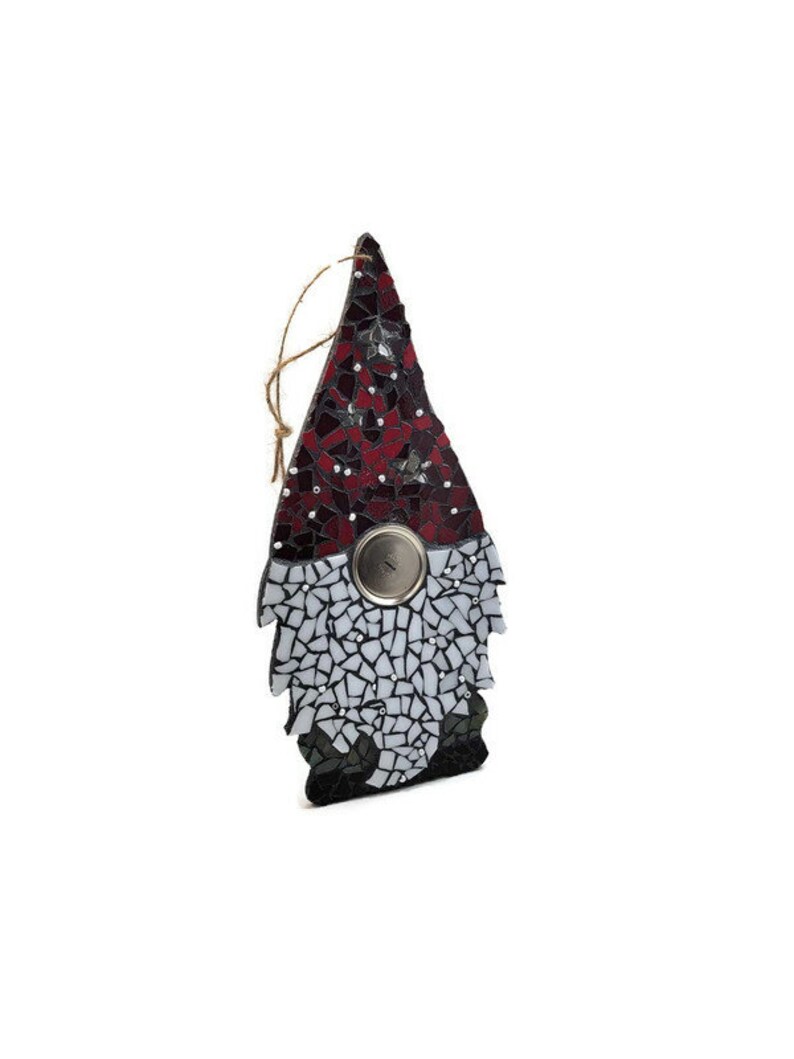 Op de afbeelding: Een moza&iuml;ek kabouter ornament met een rode en zwarte hoed en een witte baard. De kabouter heeft een metalen knoop en een touwlus om op te hangen. Het moza&iuml;ek is gemaakt van kleine, onregelmatig gevormde stukjes.