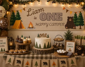 Peut inclure: Une décoration d'anniversaire sur le thème du camping avec une bannière Liam is ONE HAPPY CAMPER, un gâteau effet bouleau avec une décoration one, des cupcakes, des s'mores, une lanterne, un ours en peluche et des ballons forestiers.