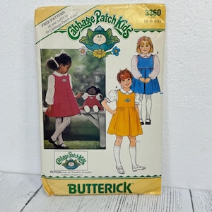May include: A Butterick sewing pattern envelope for Cabbage Patch Kids clothing, size 5-6-6X. The front features illustrations of children wearing a red jumper and a yellow jumper, along with a doll wearing a matching outfit. Text includes Cabbage Patch Kids, 3360, and bonus iron-on transfers included.