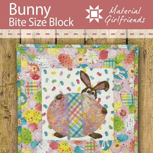 May include: A colorful quilt block featuring a bunny holding an Easter egg. The block is surrounded by a border of jelly beans and Easter eggs. The text "Bunny Bite Size Block" and "Material Girlfriends" is visible on the image.