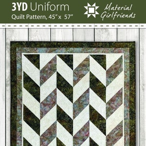 Pode incluir: Um padrão de colcha chamado "3YD Uniform" de Material Girlfriends. O padrão é para uma colcha que mede 45 polegadas por 57 polegadas. A colcha apresenta um design geométrico de triângulos pretos e brancos com um tecido estampado verde e marrom.