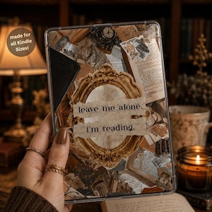 May include: A clear Kindle case featuring a collage of vintage book pages, antique clock illustrations, and a central ornate gold frame. The text "leave me alone. i'm reading." is printed across the center. A circular badge reads "made for all Kindle Sizes!"