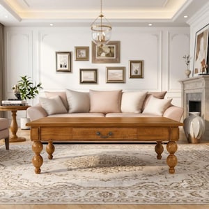 May include: A rectangular wooden coffee table with a warm brown finish, featuring a central drawer with a dark metal pull handle. The table is supported by four thick, rounded, bulbous legs that provide a sturdy base for the tabletop surface.