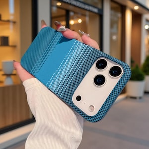 May include: A blue smartphone case featuring a gradient pattern of small squares and solid stripes. The case has a white rectangular camera cutout area with three circular lens openings and a flash, designed to fit a modern mobile device.