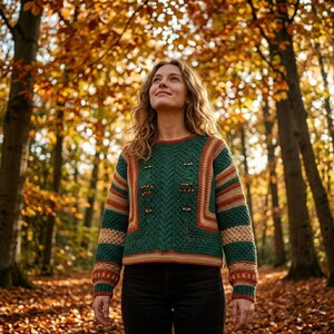 May include: A long-sleeved crochet sweater featuring a dark green central panel with vertical cable-knit textures and small gold-toned embellishments, accented by horizontal stripes in shades of orange, cream, and dark green on the sleeves.