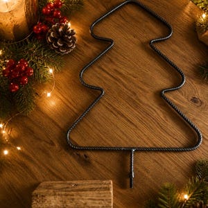 May include: A dark gray metal wire frame shaped like a stylized Christmas tree with a twisted texture. The frame features a central vertical stem at the bottom with a threaded end for attachment, designed to be mounted into a wooden base block.