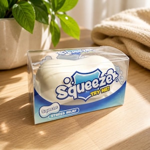 Peut inclure: Un jouet anti-stress blanc et arrondi emballé dans une boîte rectangulaire en plastique transparent. L'emballage présente des graphismes bleus et blancs avec le texte Squeeze, TRY ME! et STRESS RELIEF imprimé en lettres bleues sur le devant.