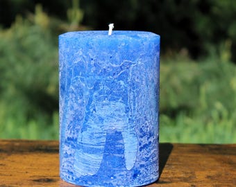 May include: A blue pillar candle with a white wick. The candle has a marbled, textured surface.