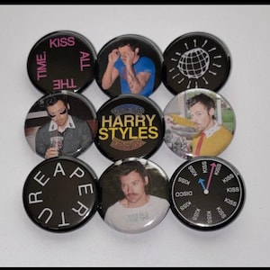May include: A collection of nine circular pin-back badges featuring various designs, including photographs of Harry Styles, text reading "KISS ALL THE TIME," "HARRY STYLES," "REAPERTURE," and "KISS DISCO," along with a globe graphic and a clock face.