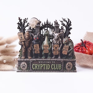 Peut inclure: Une figurine décorative représentant cinq créatures légendaires devant une grille en fer forgé et une pleine lune. Les personnages tiennent des panneaux indiquant STAY WILD, THE NIGHT SEES ALL, LEGENDS LIVE DEEP, HUNGRY FOR MORE et NO BLOOD LEFT BEHIND. WELCOME TO CRYPTID CLUB est inscrit sur la base.