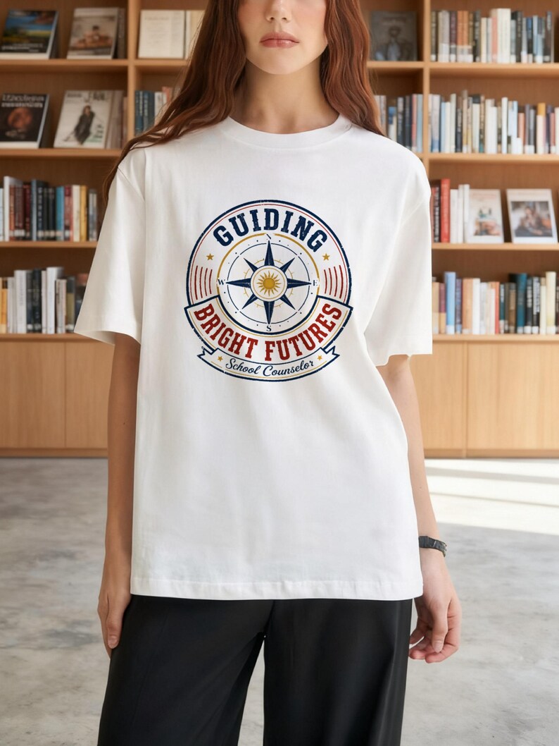 May include: A white short-sleeved t-shirt featuring a circular graphic on the chest. The design includes a central compass rose, the text "GUIDING BRIGHT FUTURES" in blue and red, and the words "School Counselor" at the bottom in blue.