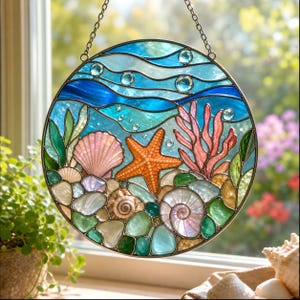 May include: A circular stained glass suncatcher featuring an underwater ocean scene with a central orange starfish, a pink seashell, a spiral shell, and pink coral. The design includes blue wavy water patterns, green seaweed, and clear glass pebbles.