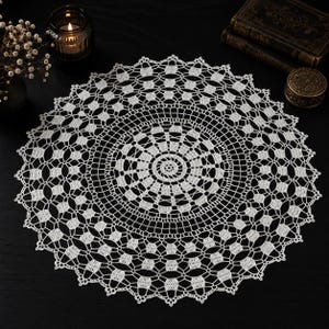 May include: A round white crochet doily featuring a complex geometric pattern with a central spiral, concentric rings of openwork stitches, and a scalloped edge. The intricate needlework displays a repeating motif of small squares and loops.