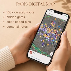 May include: A smartphone displaying a Paris digital map with numerous color-coded pins over a satellite view. Text on the screen reads PARIS DIGITAL MAP, 100+ curated spots, hidden gems, color-coded pins, and personal notes. The interface shows Google Maps.