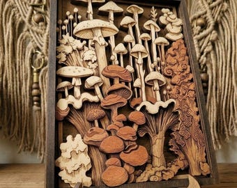 Op de afbeelding: Een rechthoekig houten wandkunstwerk met een meerlaags, lasergesneden ontwerp van diverse paddenstoelen en bosbladeren. Het kunstwerk toont verschillende tinten natuurlijk hout, variërend van lichtbeige tot donkerbruin.