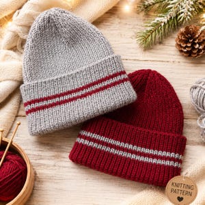 May include: Two knit beanies, one light gray with two dark red stripes on the cuff and one dark red with two light gray stripes on the cuff. Both hats feature a ribbed texture and a folded brim design, presented alongside knitting supplies.