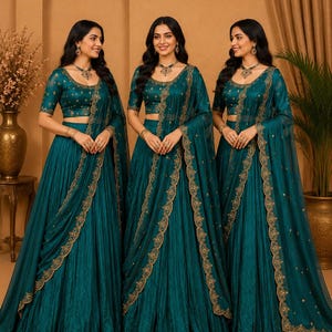 May include: A teal lehenga choli set featuring a pleated skirt, a matching short-sleeved blouse, and a sheer dupatta. The ensemble is decorated with intricate gold embroidery along the borders and small gold motifs throughout the fabric.