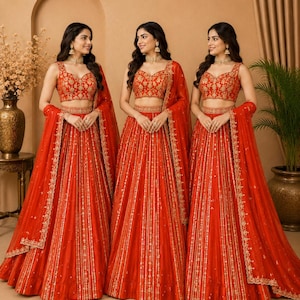 May include: A vibrant orange lehenga set featuring a sleeveless blouse and a floor-length skirt, both adorned with intricate gold embroidery. The ensemble includes a matching sheer orange dupatta with a gold-embroidered border and a gold choker.