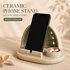 May include: A speckled light green ceramic phone stand with a curved back, a front ledge for a smartphone, and a small circular tray containing white earbuds. Text reads: CERAMIC PHONE STAND, POTTERY TEMPLATE PDF, INSTANT DOWNLOAD.