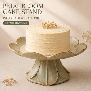 Puede incluir: Un soporte para pasteles de cerámica verde salvia con base y borde en forma de pétalos, que sostiene un pastel redondo glaseado con pequeñas flores blancas. El texto PETAL BLOOM CAKE STAND POTTERY TEMPLATE PDF INSTANT DOWNLOAD es visible.