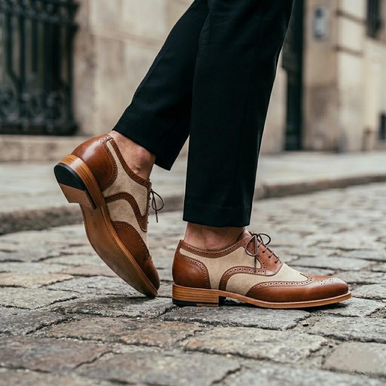 Low angle shot of a man walking in brown and white wingtip shoes and black formal trousers.